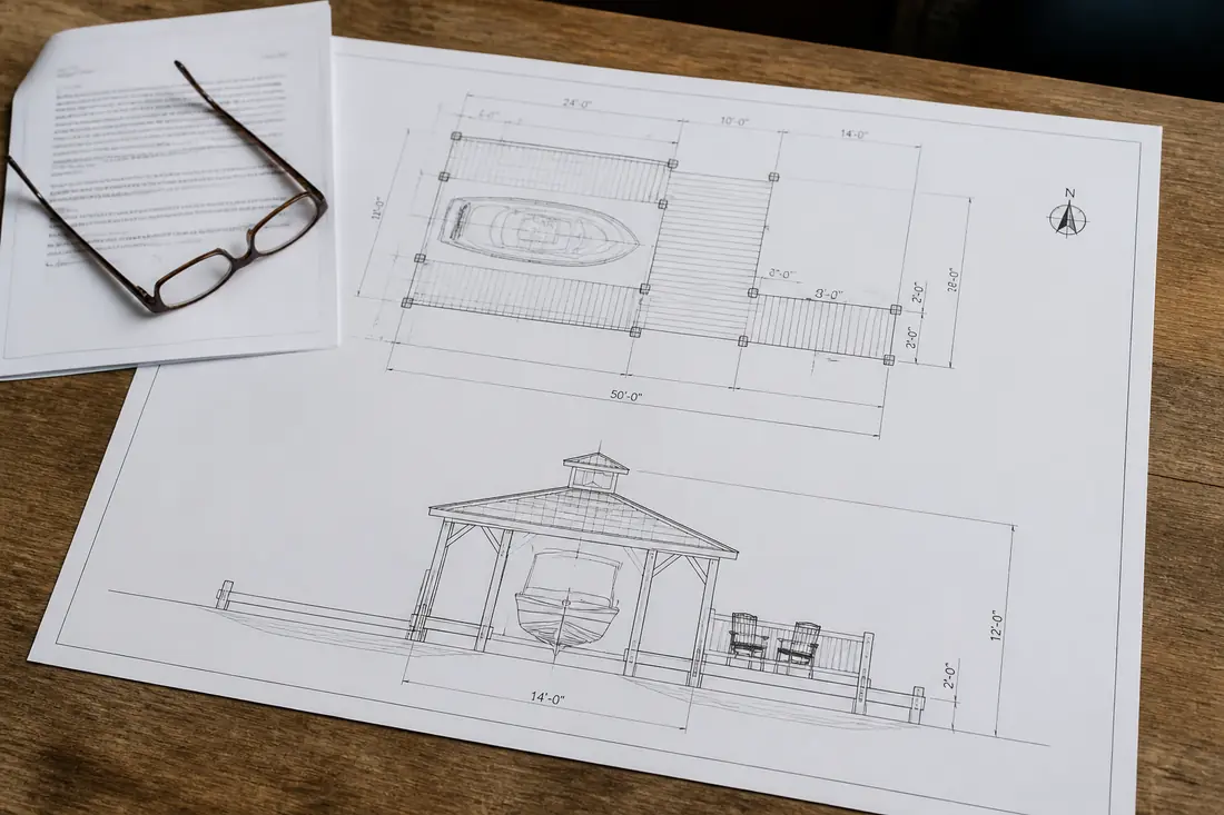 A plan and elevation drawing of a dock on a desk beside a letter